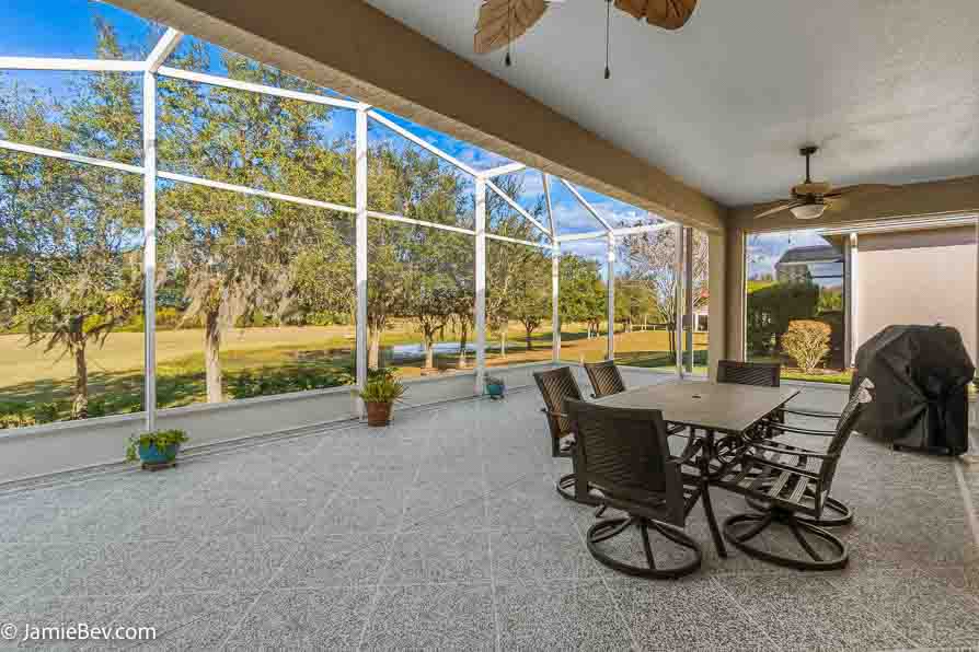 Open living room with sliding glass doors opening to a screened lanai with golf course views.