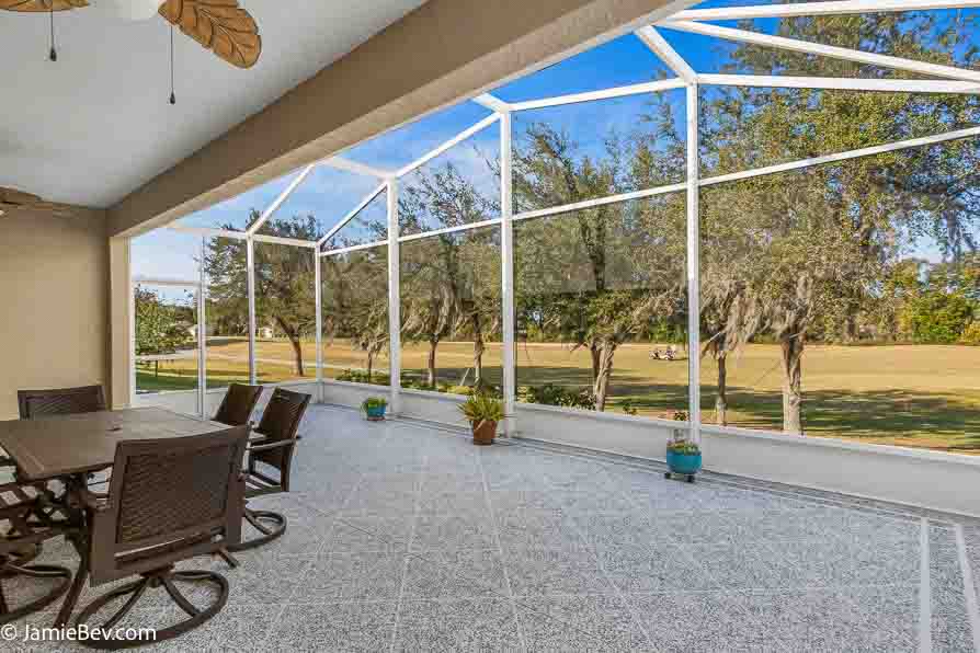 Open living room with sliding glass doors opening to a screened lanai with golf course views.