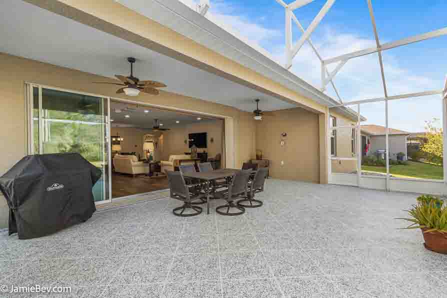 Open living room with sliding glass doors opening to a screened lanai with golf course views.