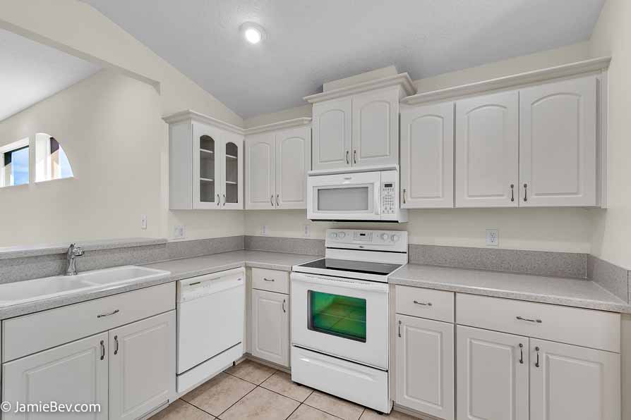 Kitchen with stainless steel appliances, a spacious countertop, and a cozy breakfast nook with bay windows.