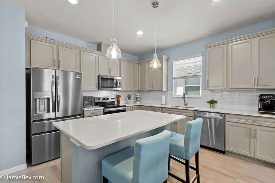 Designer kitchen with stone gray cabinets, quartz countertops, and stainless-steel appliances.