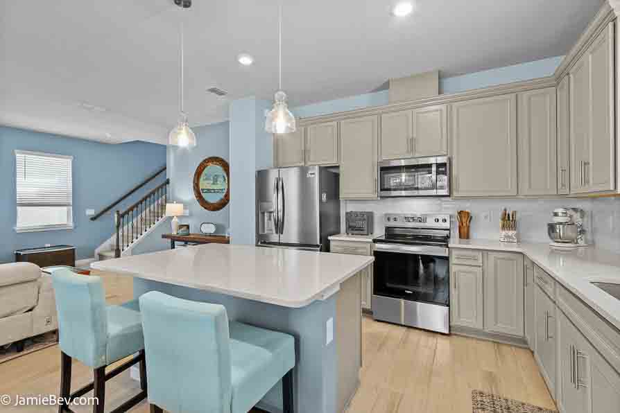 Designer kitchen with stone gray cabinets, quartz countertops, and stainless-steel appliances.
