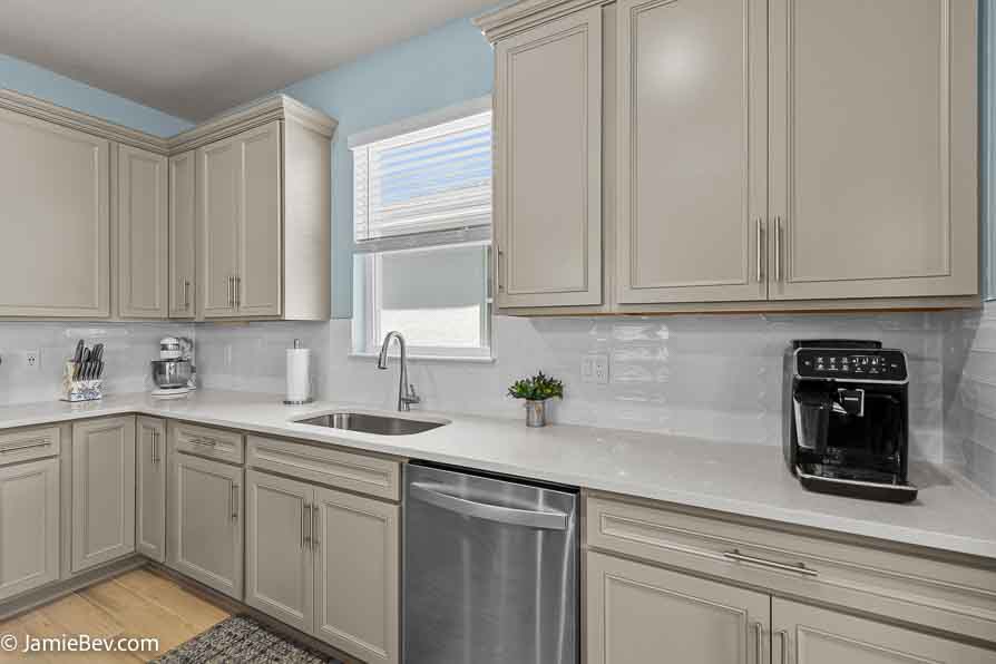 Designer kitchen with stone gray cabinets, quartz countertops, and stainless-steel appliances.