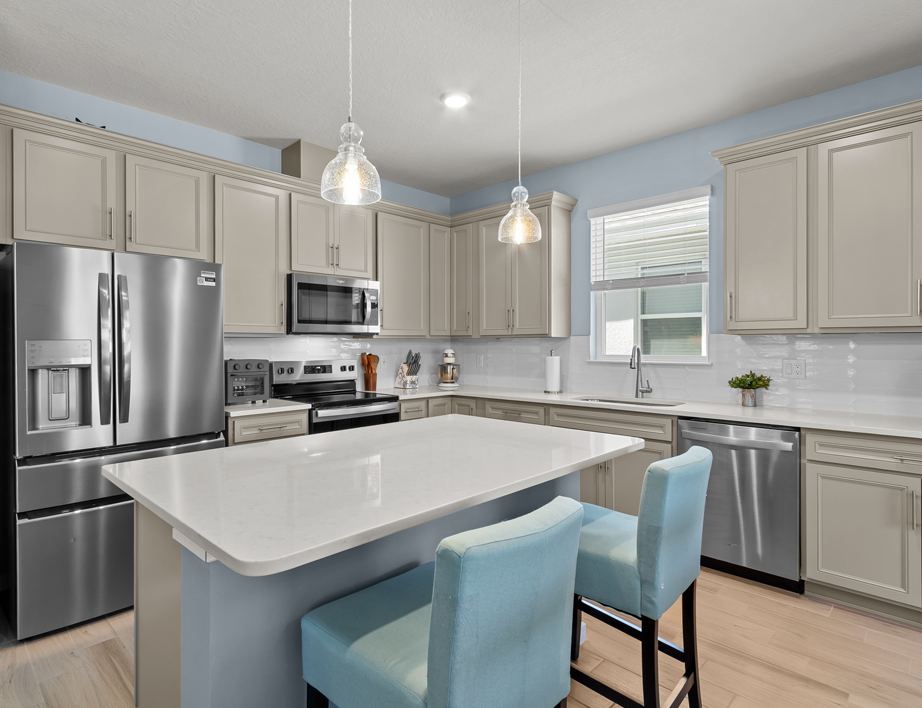 Designer kitchen with stone gray cabinets, quartz countertops, and stainless-steel appliances.